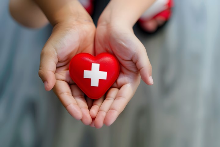 Hands holding a red heart with a medical cross